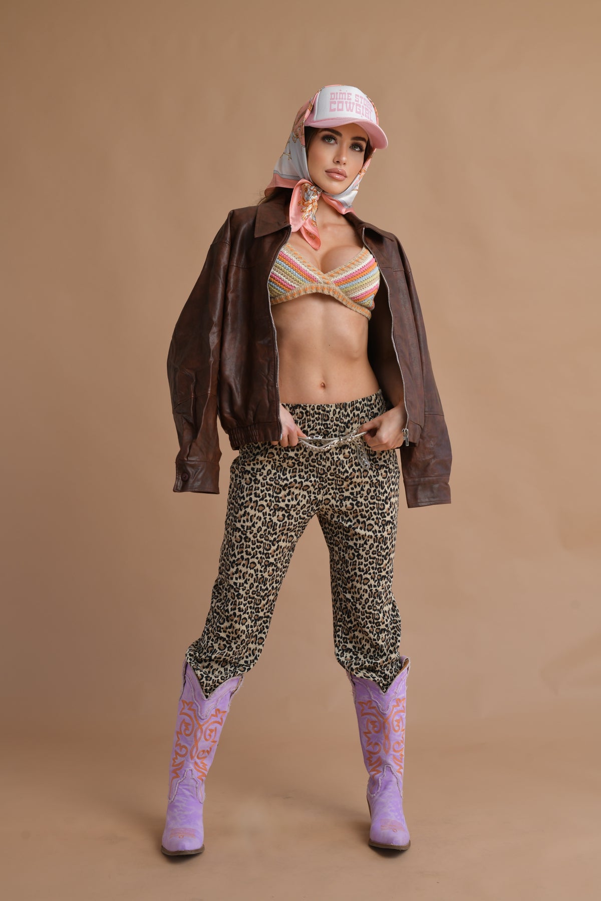 A stylish boho crochet bralette with multicolor stripes, featuring a deep V-neckline and a snug fit, paired with leopard-print pants.