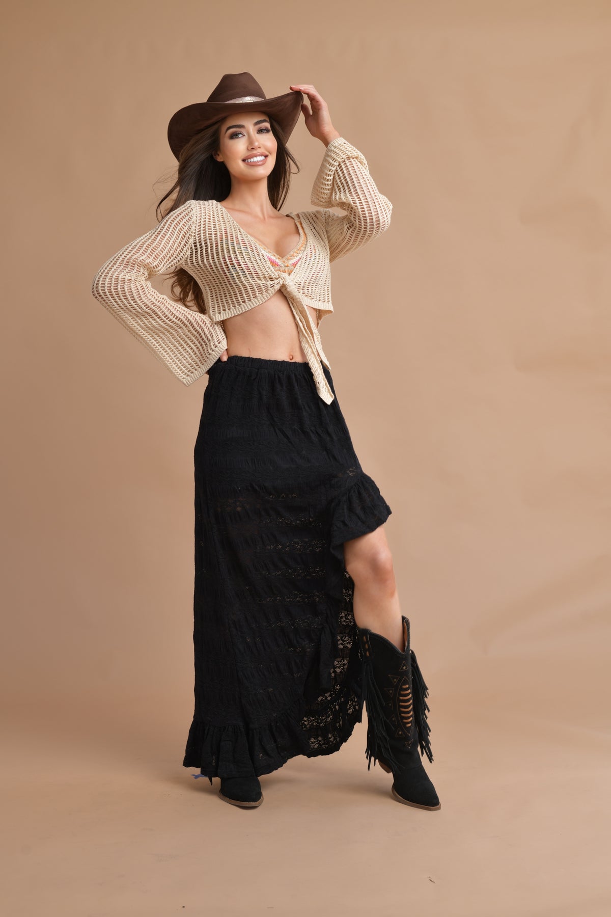 Model wearing a beige crochet cowgirl front-tie shirt with a black maxi skirt and western boots
