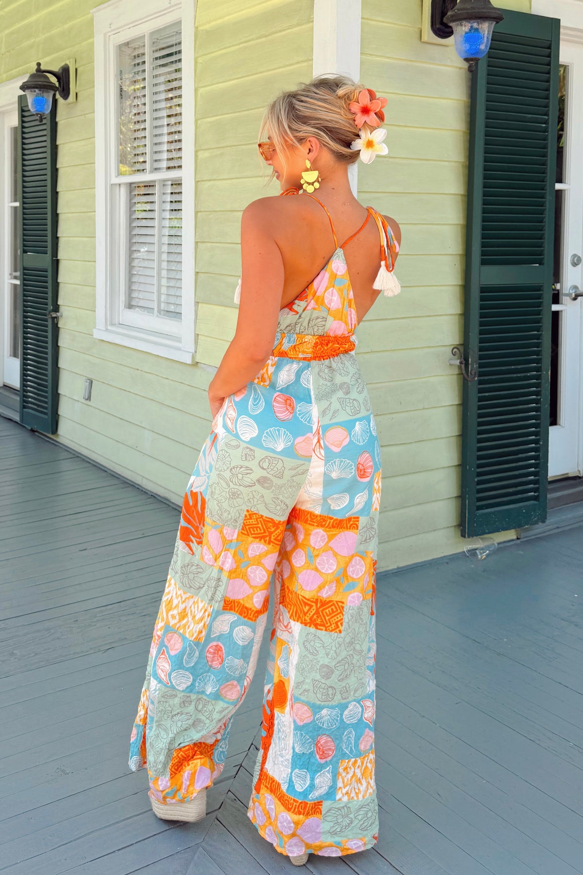 Printed boho-style jumpsuit with tassel shoulder ties and sunny vacation flair
